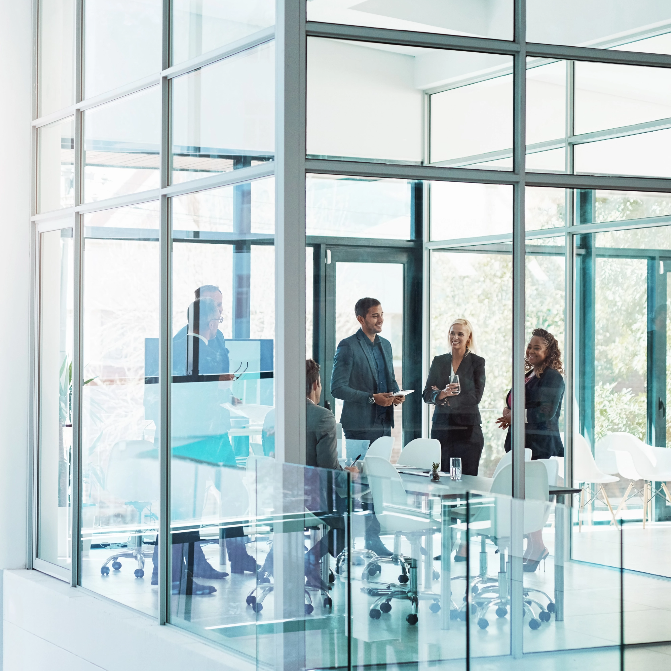 D&O Maßgeschneidert für Ihre Bedürfnisse Eine Teambesprechung findet in einem Eckbüro mit Glasfenstern statt