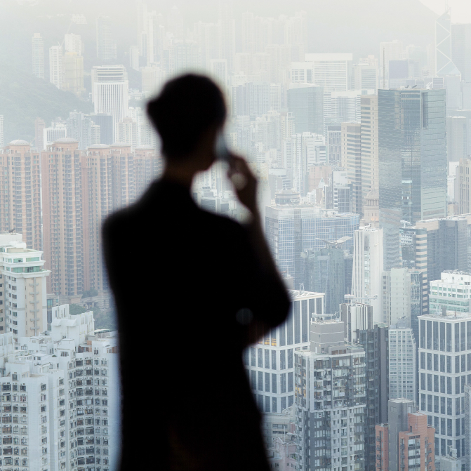 Highlights der Vertrauensschaden-Versicherung Eine Führungskraft telefoniert, während sie die Skyline einer Stadt betrachtet